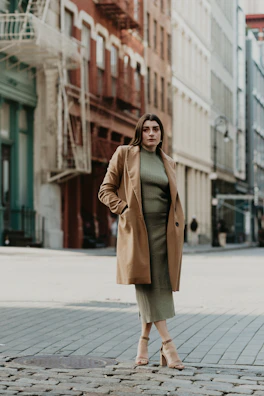 A model wearing a tailored camel coat walking confidently on a city street.