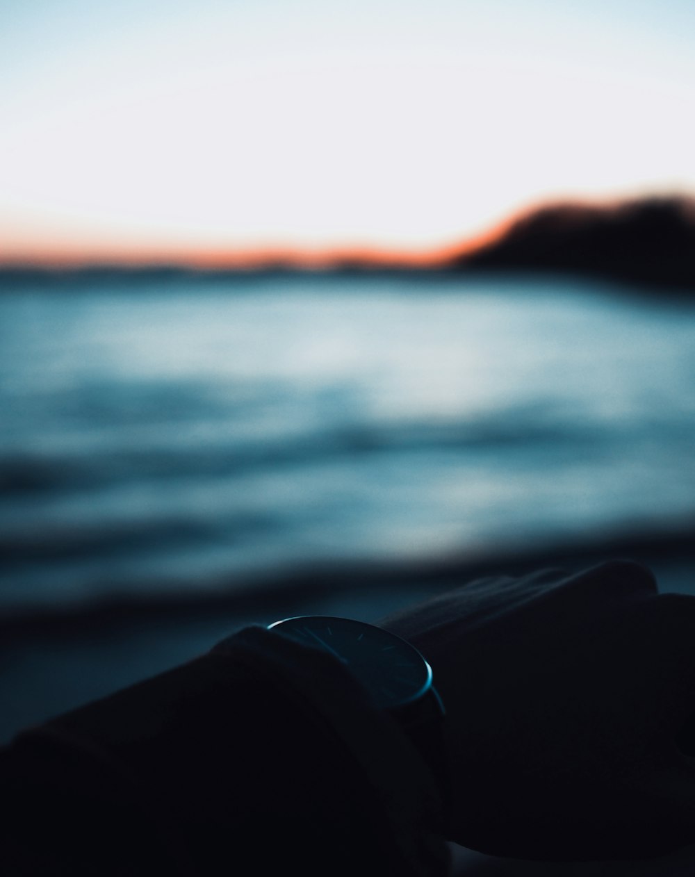 blue and white ceramic mug near body of water during sunset