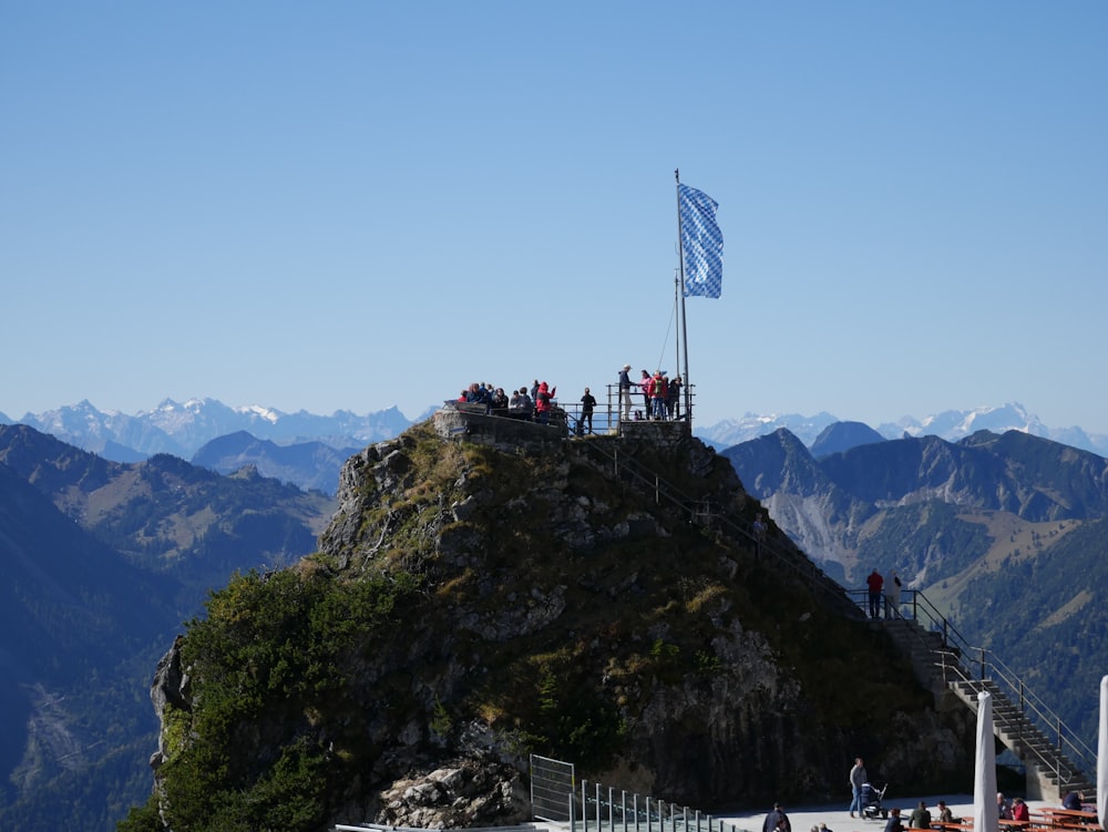 people on top of mountain with us flag during daytime