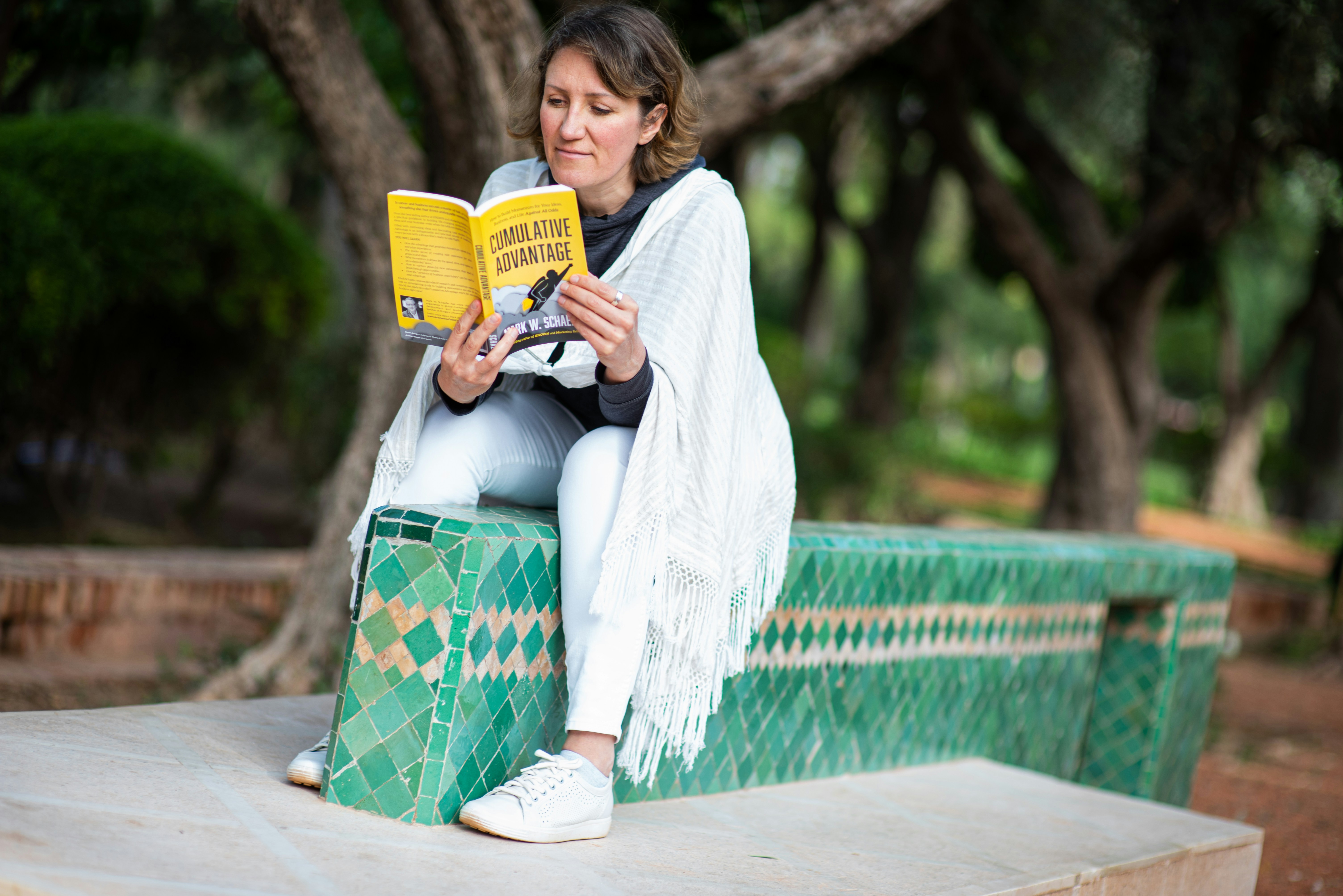 A woman reading a paperback book while relaxing in the park in Marrakech, Moro