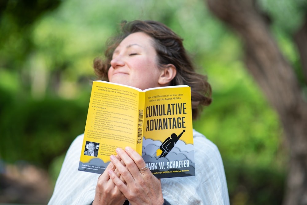 woman in white shirt holding yellow book