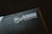 A close-up of a product packaging with the logo 'Glorious PC Gaming Race' printed in white on a dark background. The package features a stylized profile of a bearded face with flowing hair.