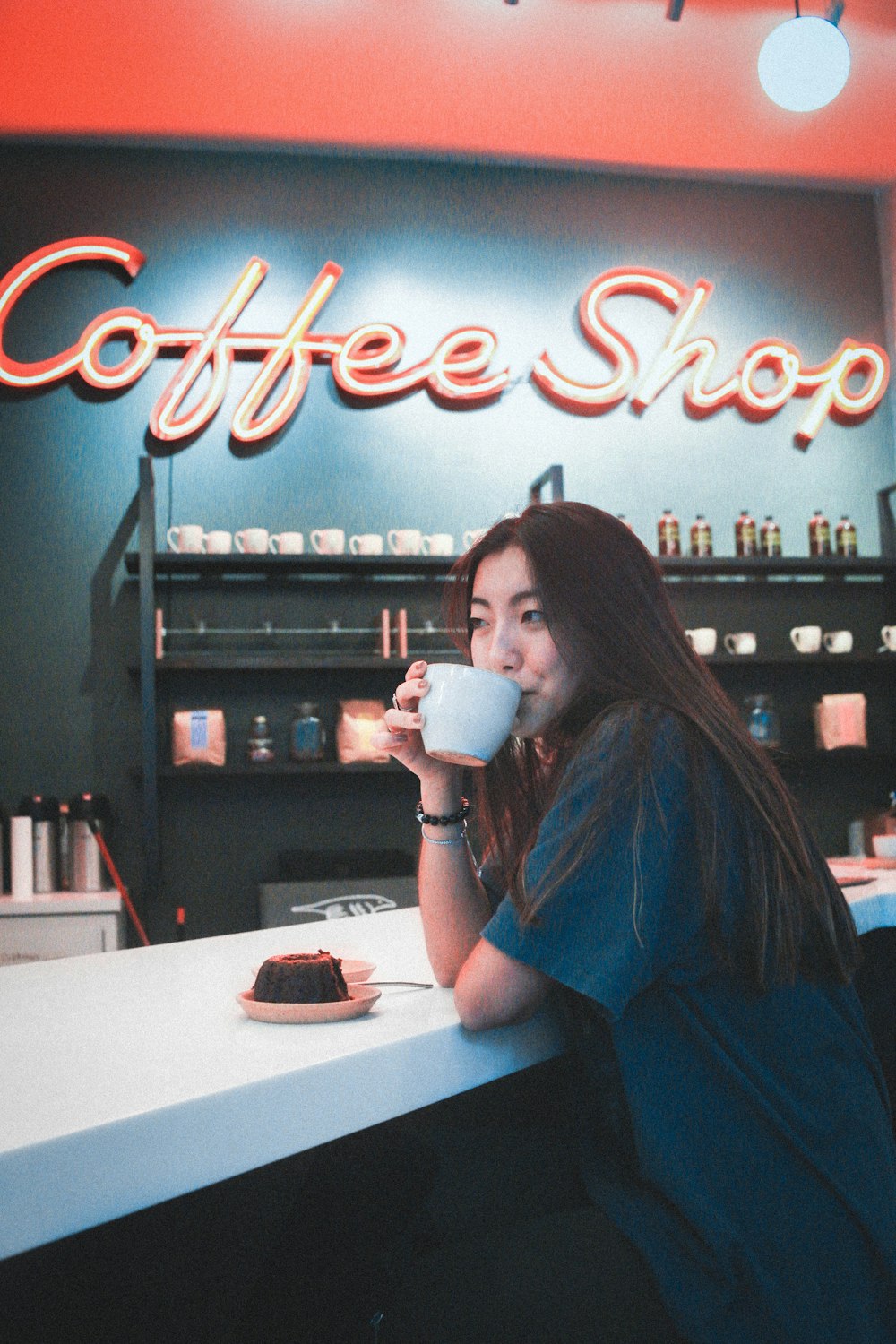 woman in blue shirt drinking from white ceramic mug