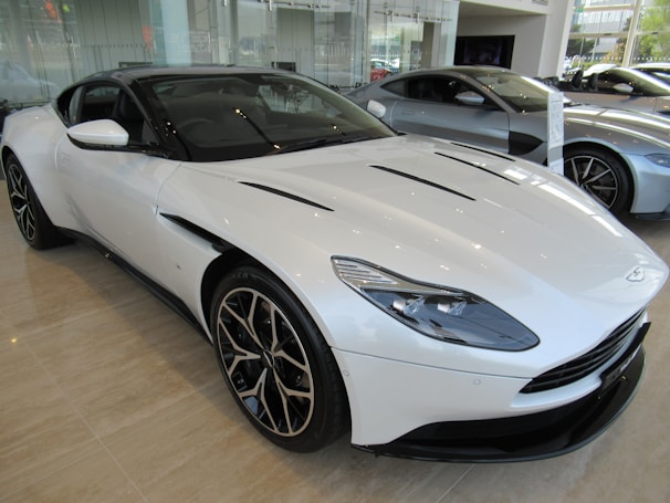 A white sports car gleaming under bright showroom lights with gold accents