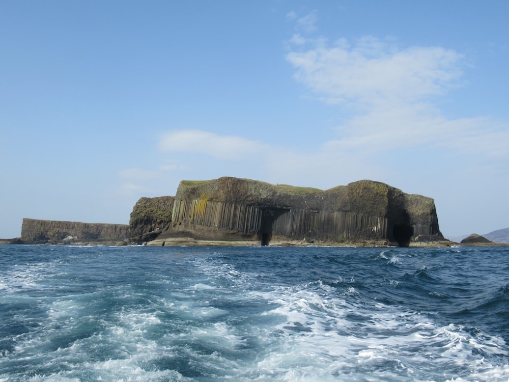 brown and green rock formation beside body of water during daytime