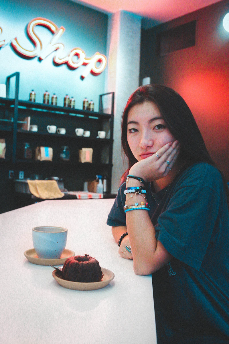 A woman in a green shirt seated at a sunlit table