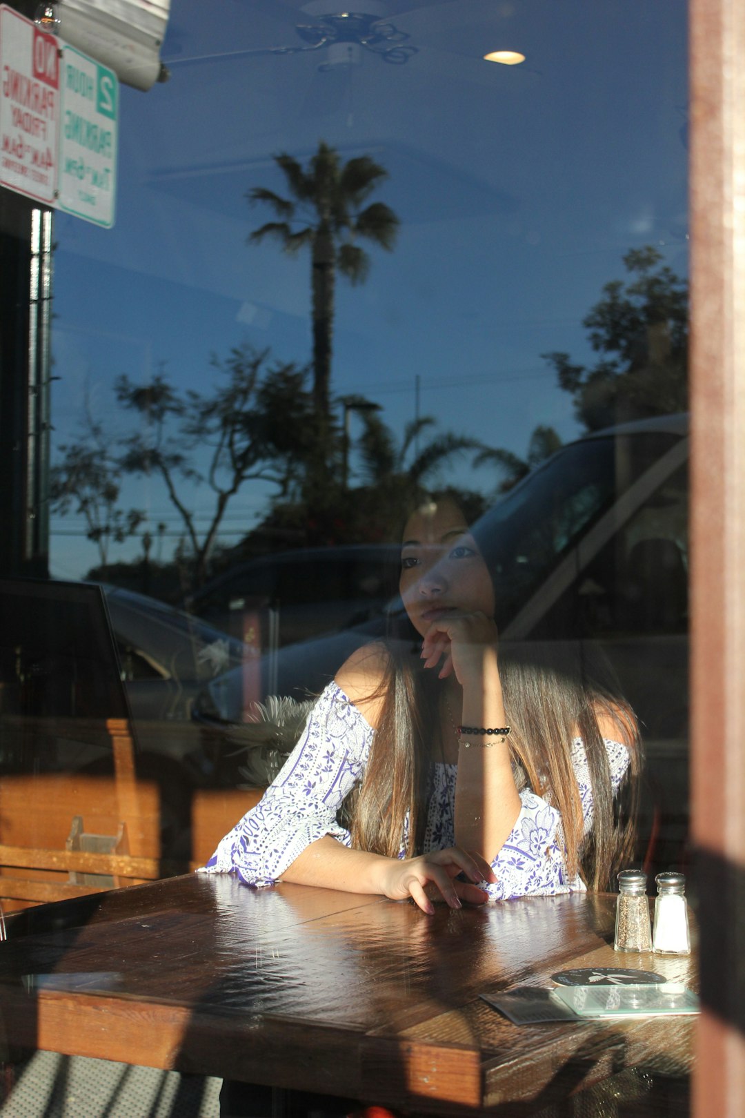 woman in white floral dress sitting on brown wooden bench during daytime