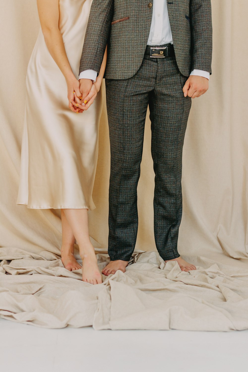 Hombre con chaqueta de traje gris y mujer con vestido beige