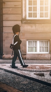 man in black coat and pants standing on sidewalk during daytime