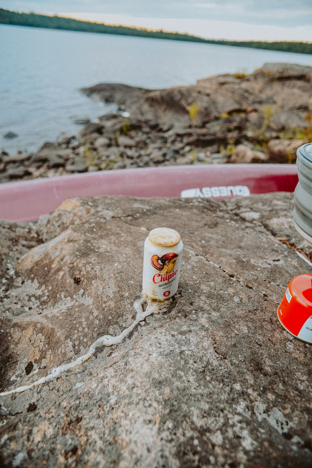 white and red plastic cup on brown sand near body of water during daytime