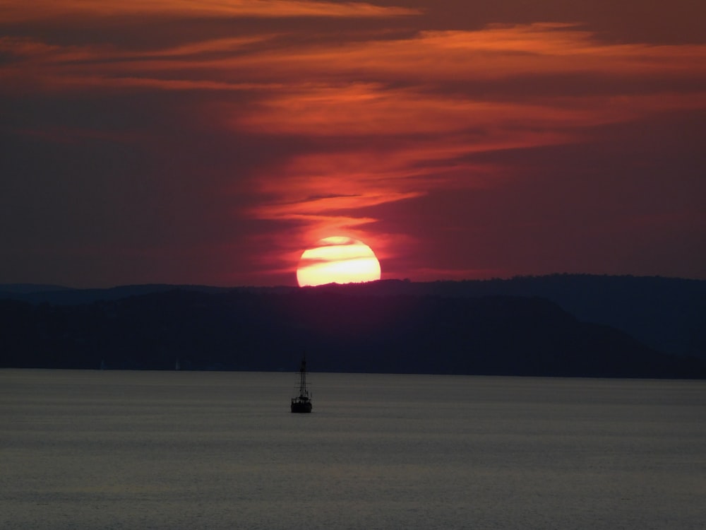 silhouette of person standing on sea shore during sunset