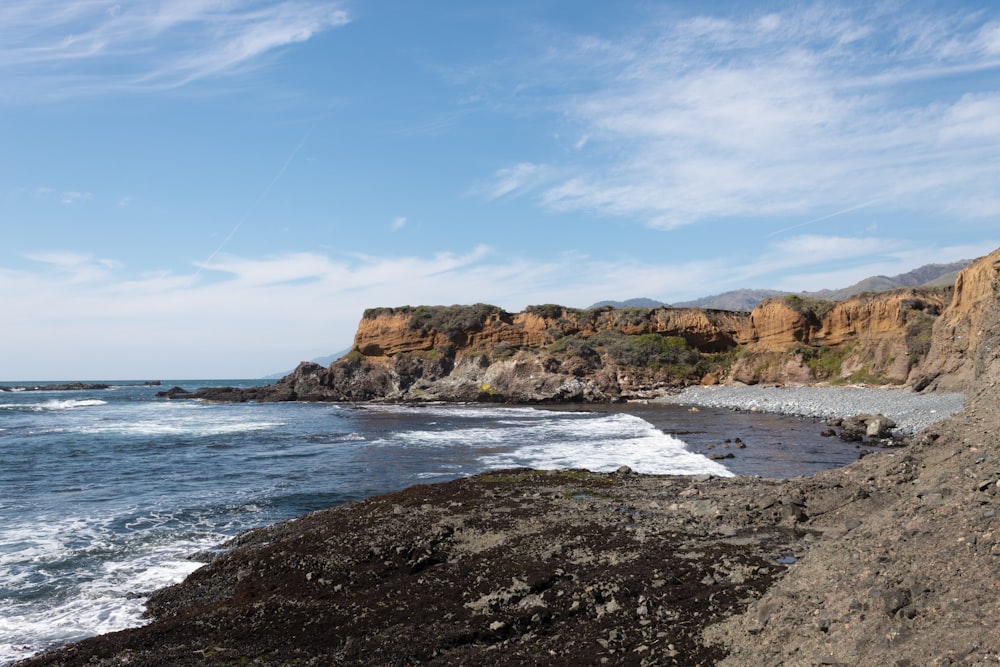 brown rock formation beside sea during daytime