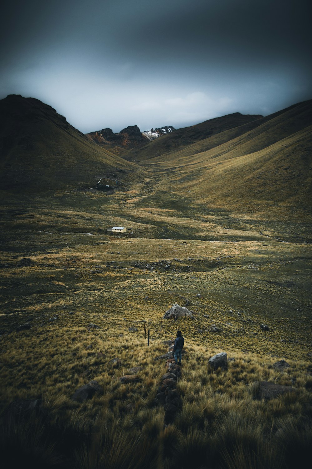 green grass field near brown mountain under white clouds during daytime