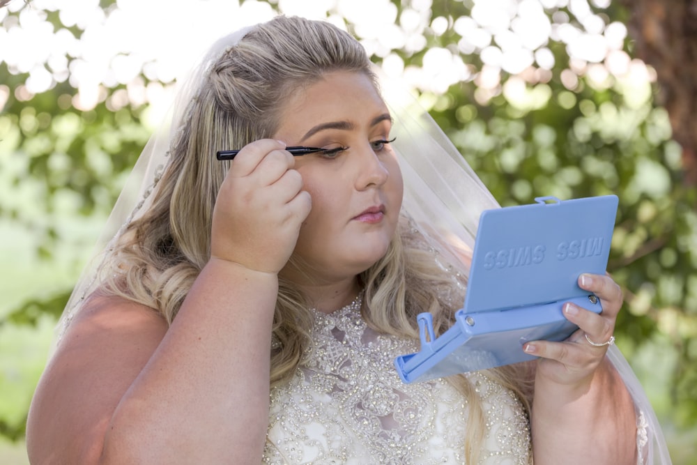 woman in white floral dress holding blue tablet computer