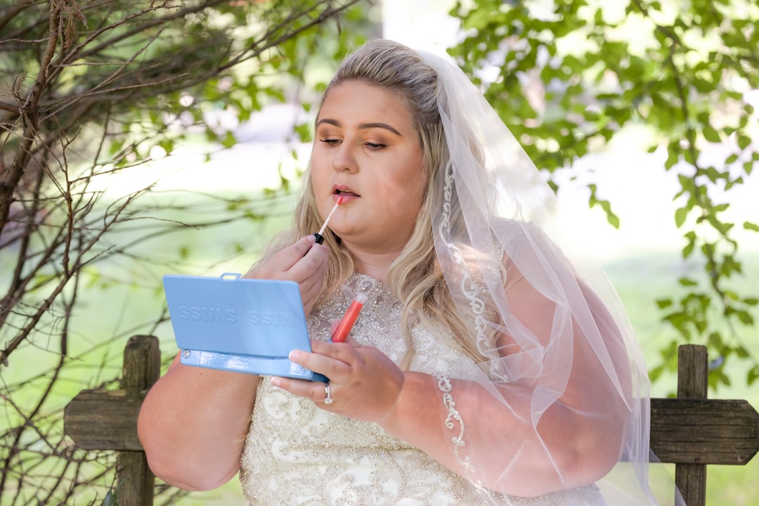 woman in white lace dress holding red pen and white book