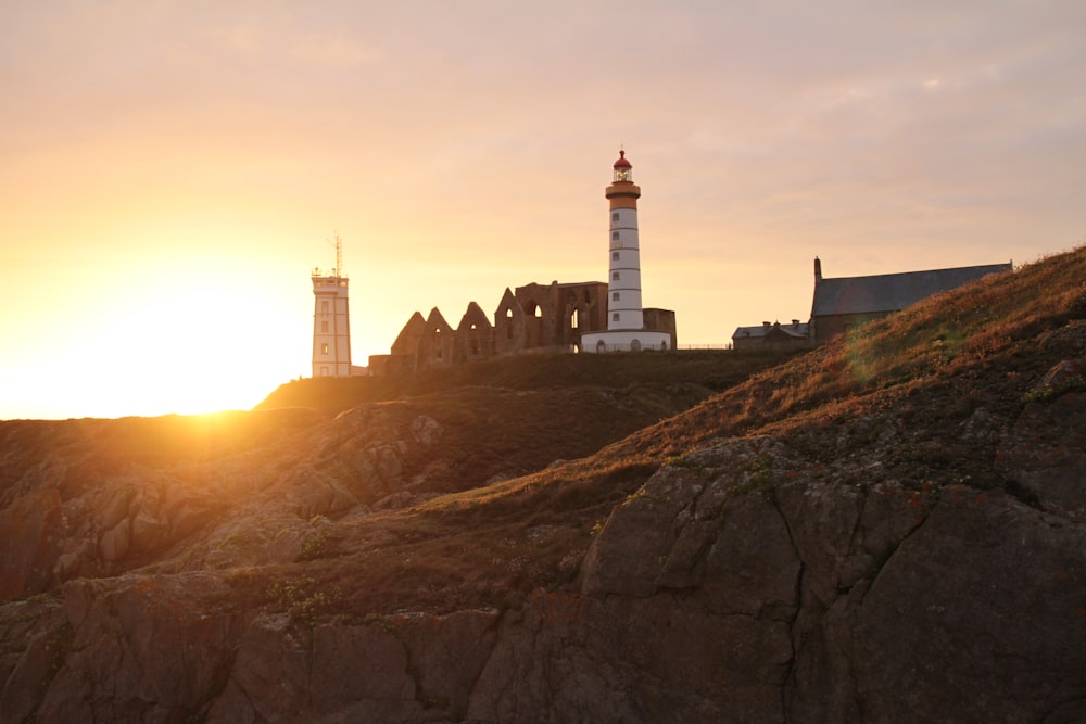 white and black lighthouse on brown hill during sunset