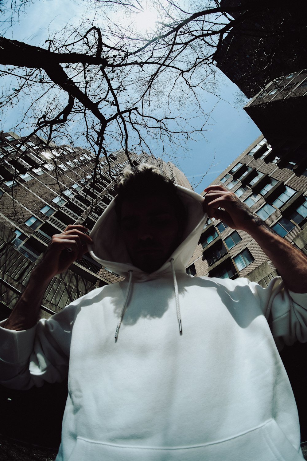 man in white shirt holding on bare tree during daytime