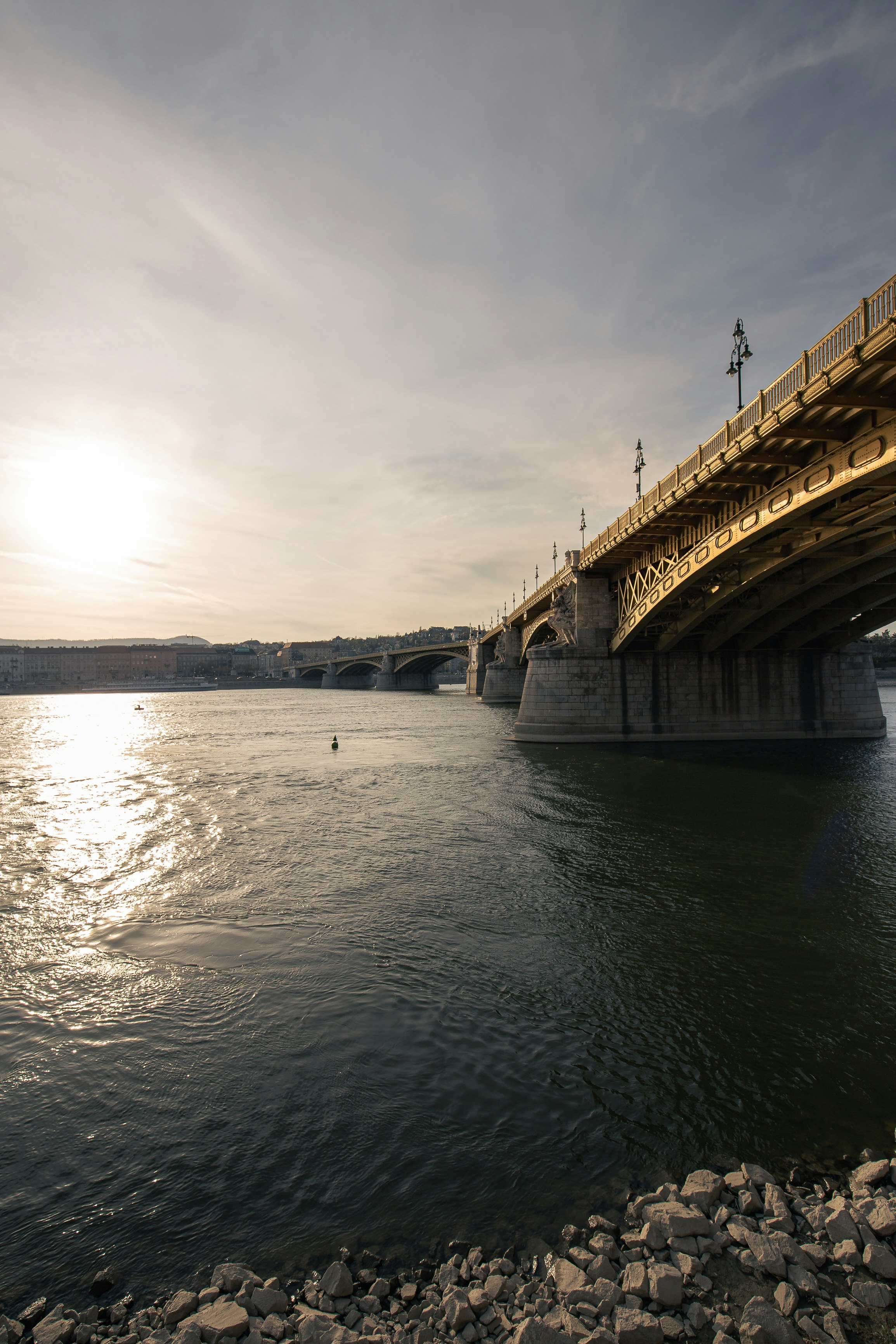 brown concrete bridge over river under cloudy sky during daytime