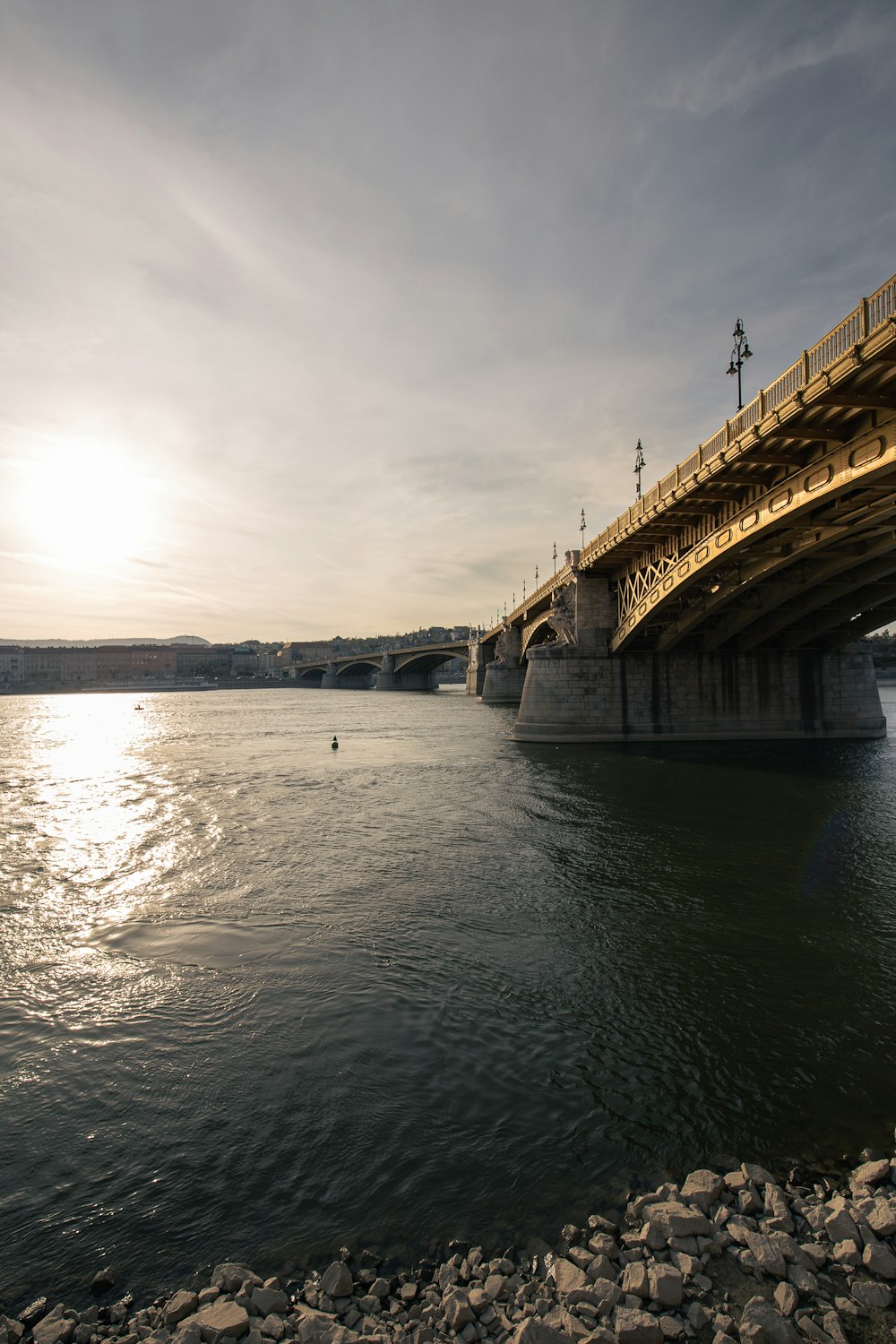 ponte de concreto marrom sobre o rio sob o céu nublado durante o dia