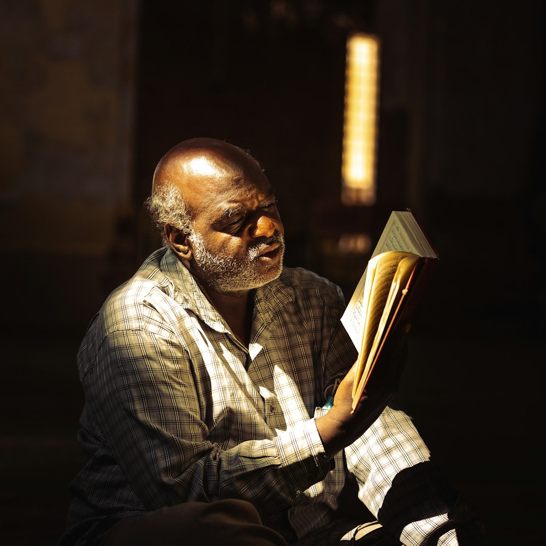 man in white and black plaid dress shirt reading book