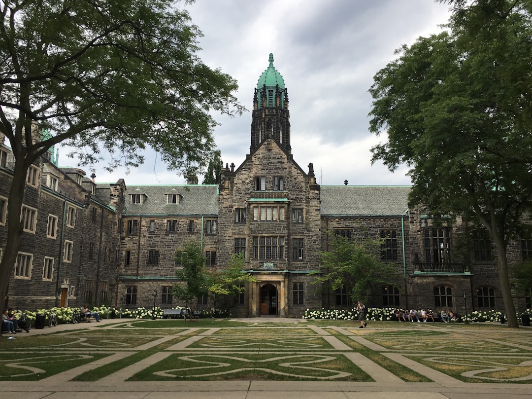 brown and gray concrete building near green trees under blue sky during daytime, Trinity College at University of Toronto<p></figure>