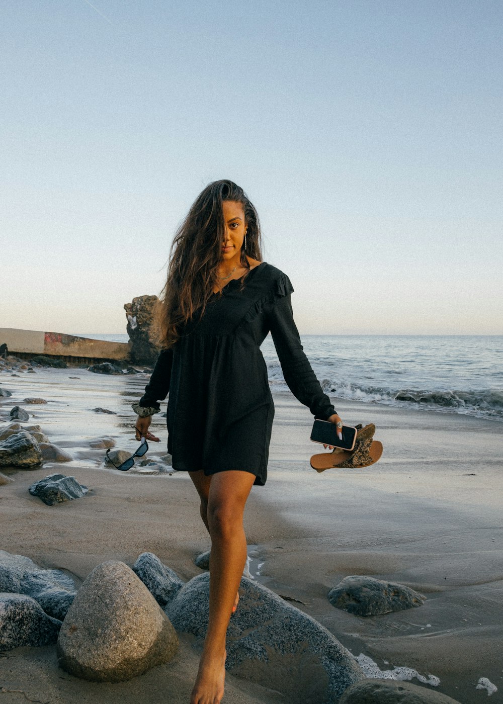 woman in black long sleeve dress holding brown acoustic guitar standing on gray rock near body