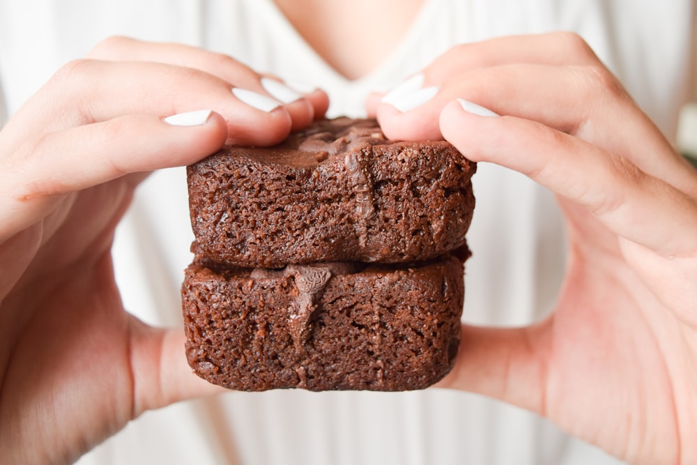 person holding chocolate cake with white icing