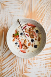 white and brown ceramic bowl with cereal and stainless steel spoon