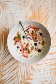 white and brown ceramic bowl with cereal and stainless steel spoon