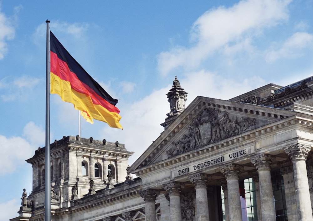 Weißes Betongebäude mit Flaggen unter blauem Himmel tagsüber