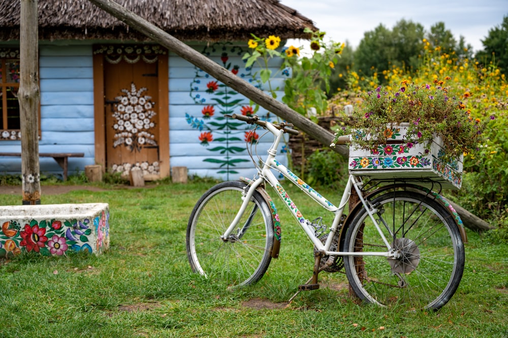 blue and white commuter bike parked beside brown wooden house during daytime