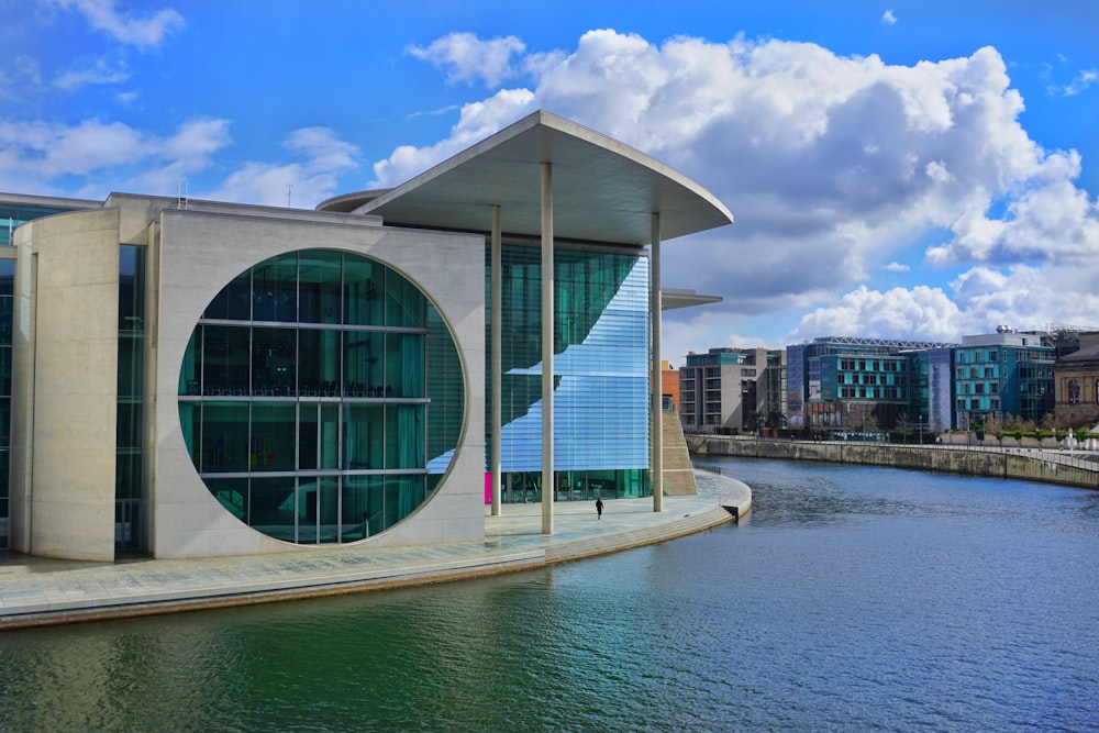 white and blue glass building near body of water during daytime