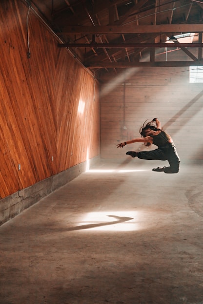 A warm, earthy-toned photo of a biodanza session in progress, with participants moving freely in a sunlit room.