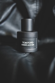 Neom Leather perfume bottle resting on textured leather with soft lighting.