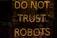 A neon sign displaying the words 'DO NOT TRUST ROBOTS' with a dark background and various reflections. The letters are illuminated in a warm yellowish-orange color, creating a stark contrast against the dim setting.