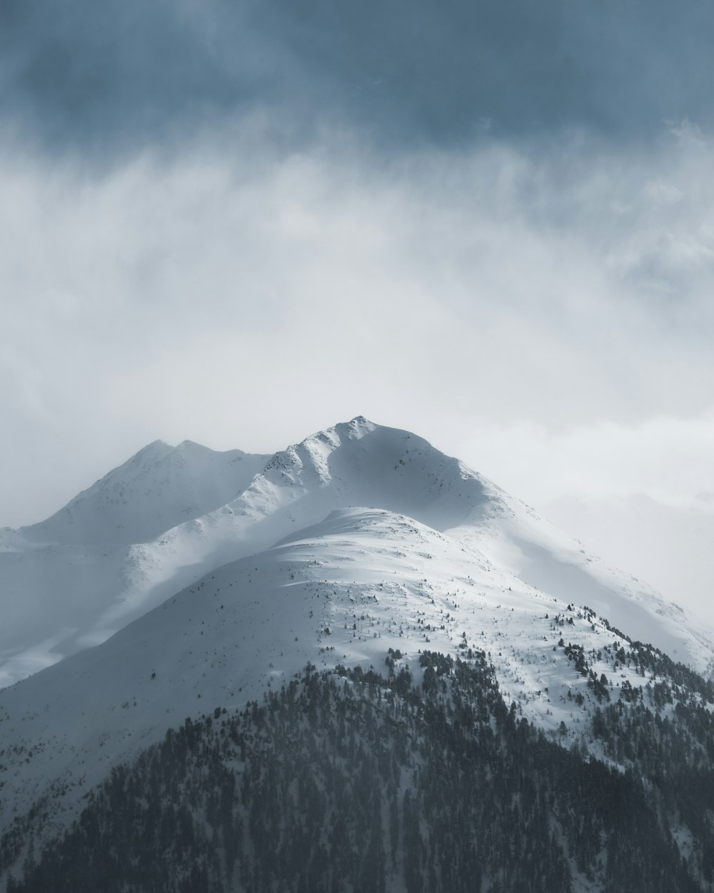 snow covered mountain under white clouds during daytime