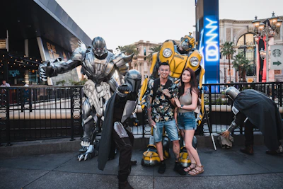A group of people smiling and interacting with an animated robot on a sunny sidewalk.