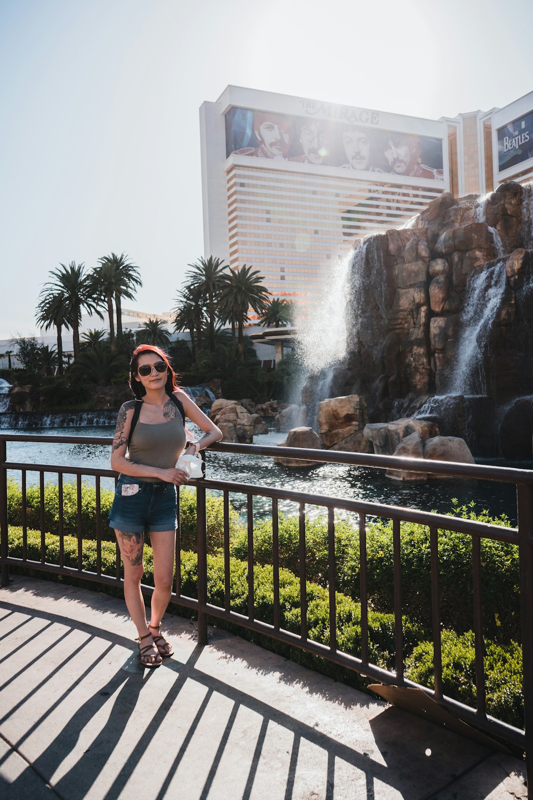 woman in white tank top and blue denim shorts standing near water fountain during daytime