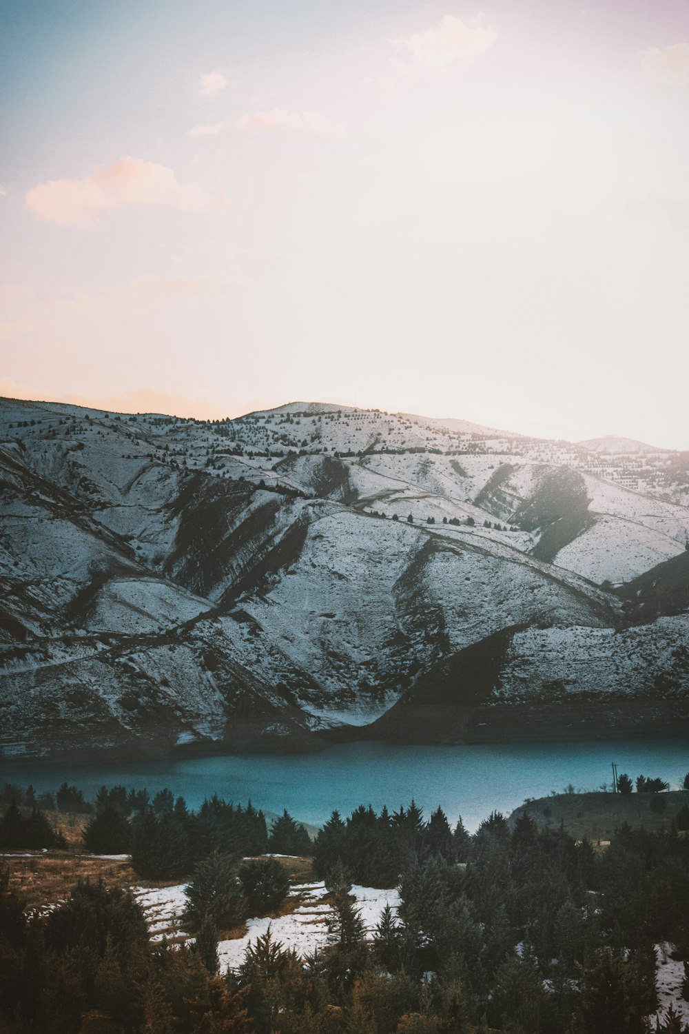 snow covered mountain near body of water during daytime