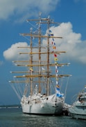 white and brown ship on sea under white clouds and blue sky during daytime
