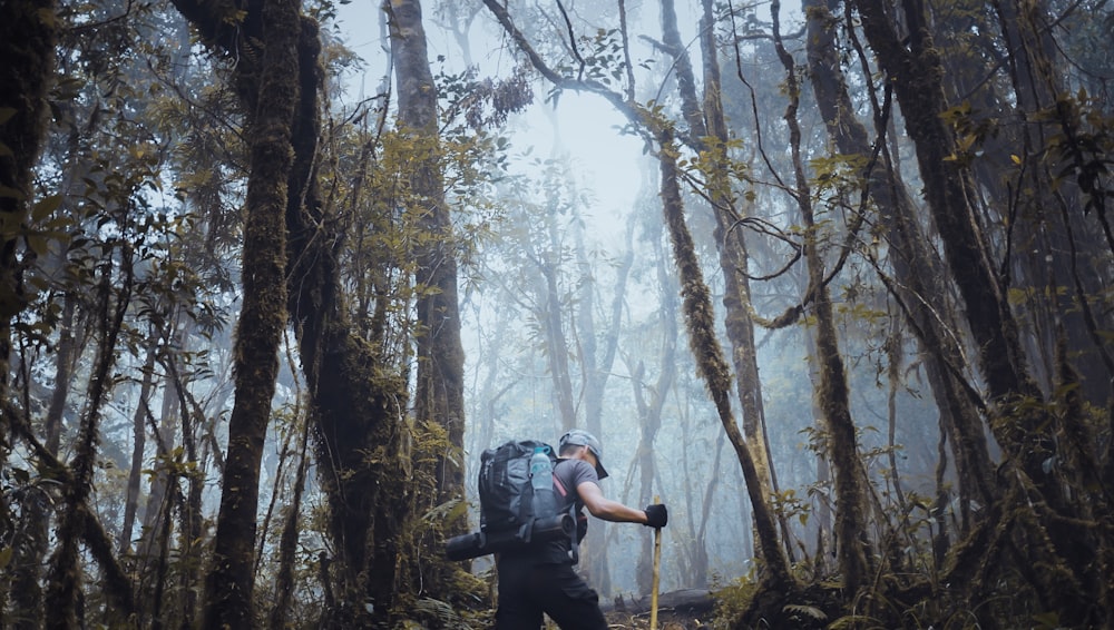 uomo in giacca nera e pantaloni neri in piedi sulla foresta durante il giorno