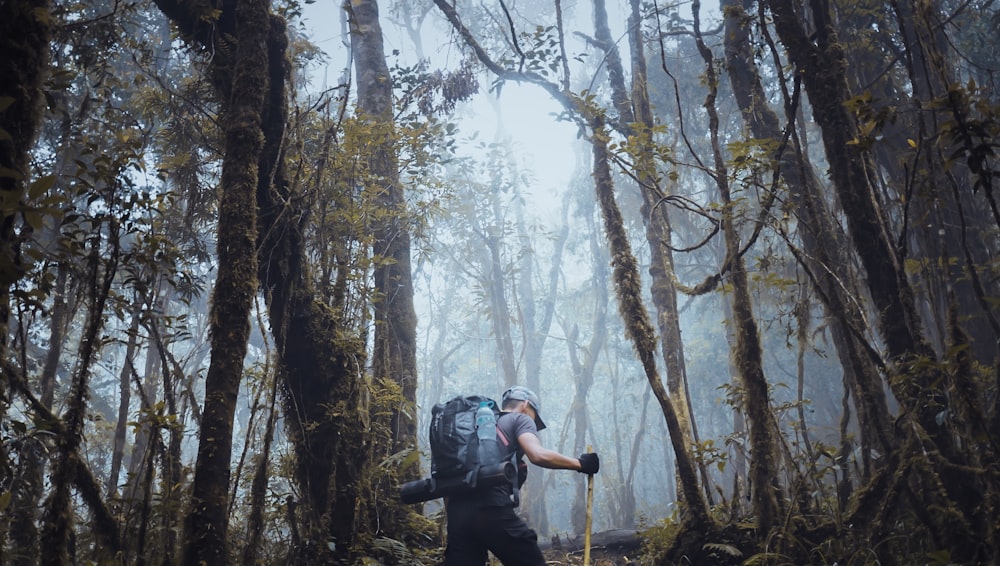 man in black jacket and black pants standing on forest during daytime