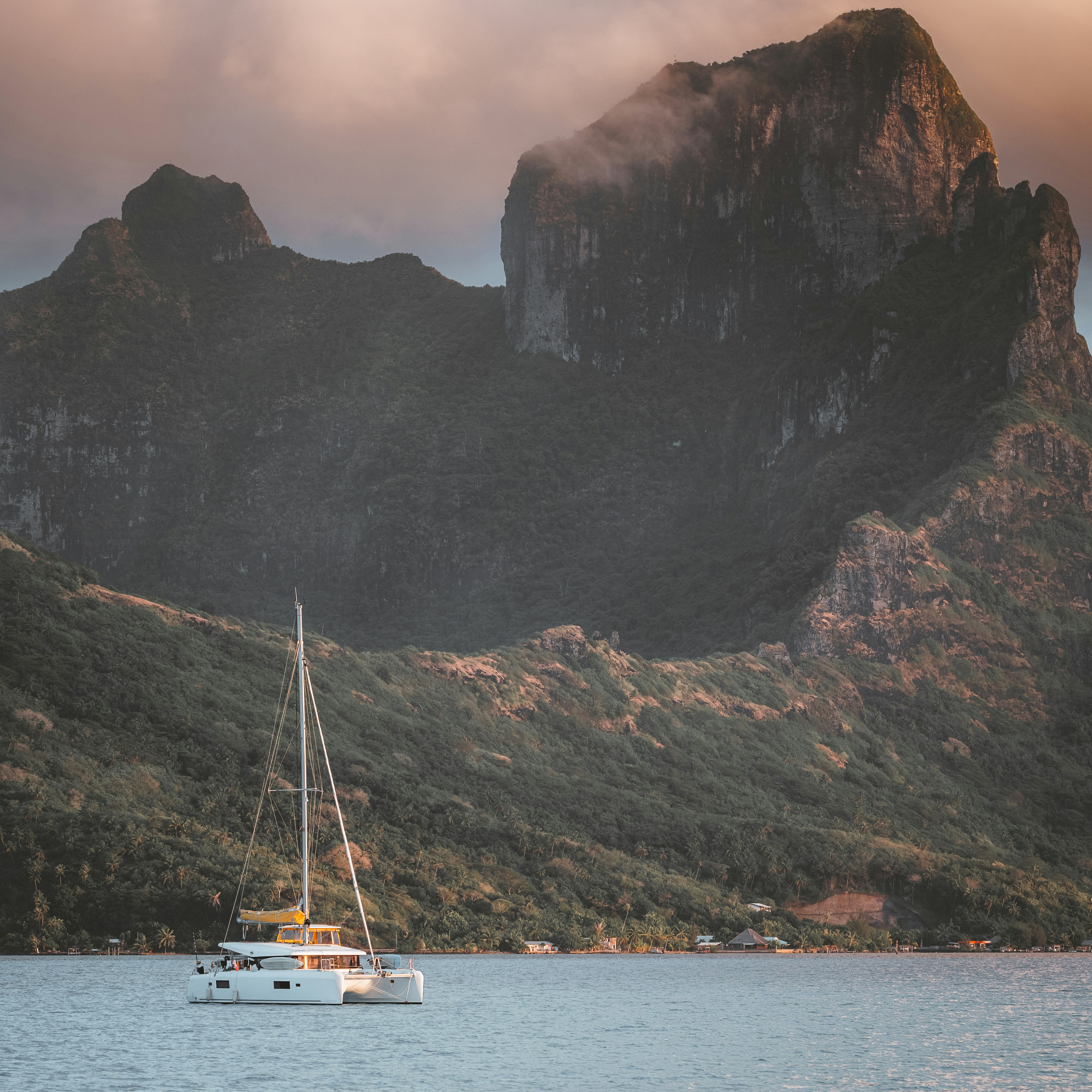 white boat on body of water near mountain during daytime