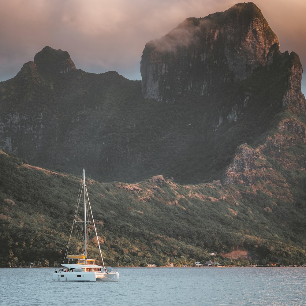 white boat on body of water near mountain during daytime