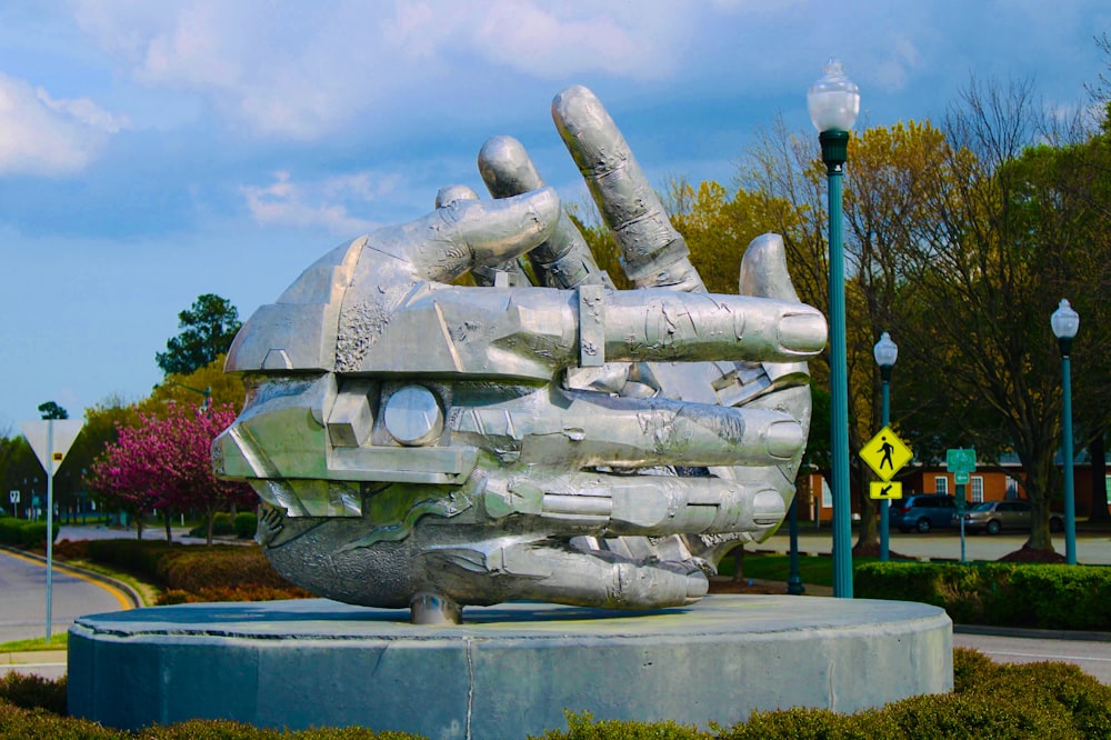 estátua de concreto cinza perto da cerca de metal azul durante o dia