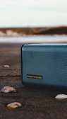 black and gray jbl portable speaker on gray sand during daytime