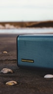 black and gray jbl portable speaker on gray sand during daytime