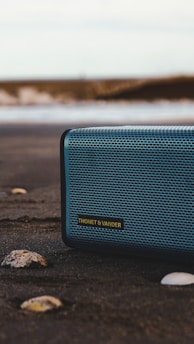 black and gray jbl portable speaker on gray sand during daytime