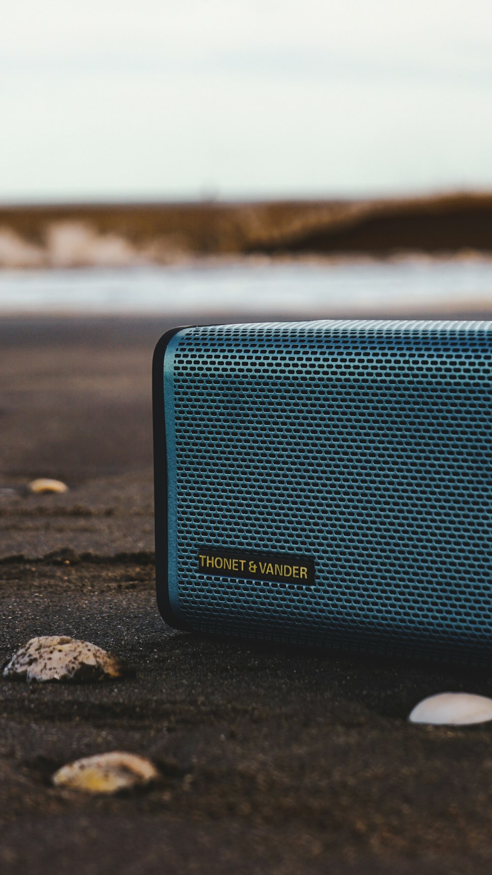 black and gray jbl portable speaker on gray sand during daytime