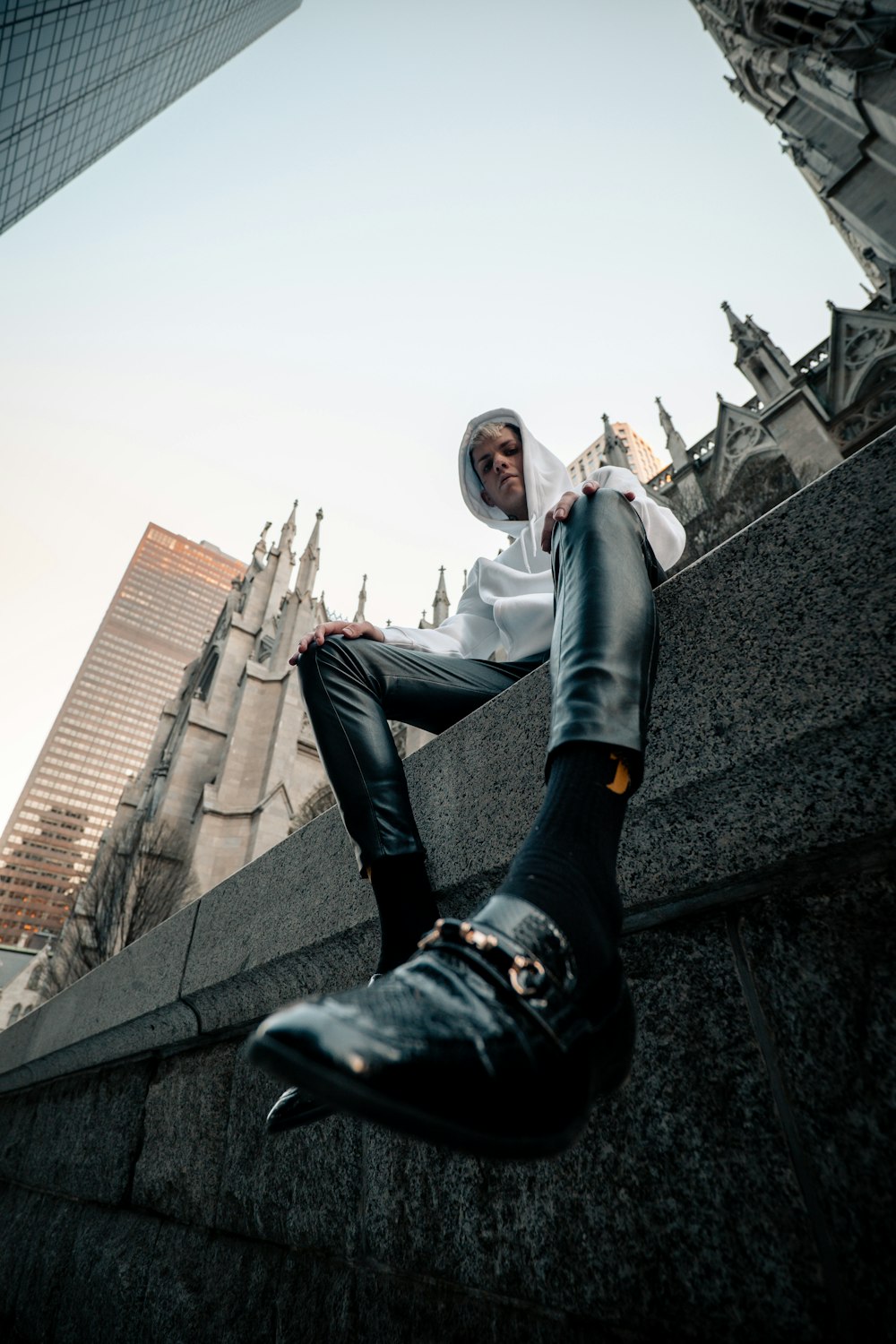 woman in gray jacket and blue denim jeans sitting on gray concrete wall during daytime